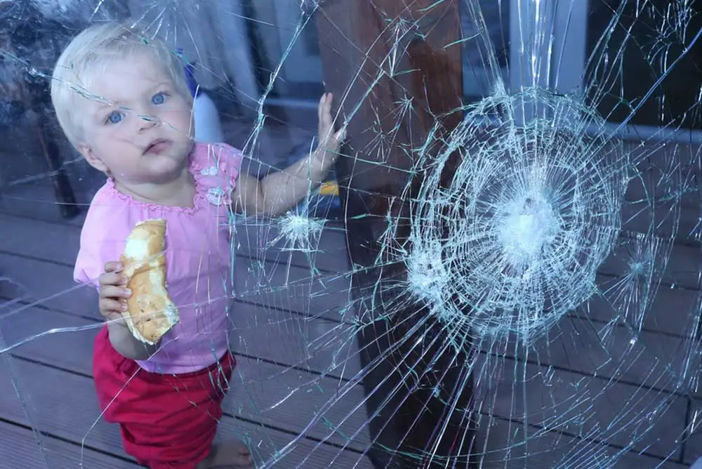 copil care sta sub geam spart cu folie antiefractie